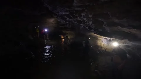 People exploring a dark flooded cave in Jumandy Caverns Stock Footage 334934323