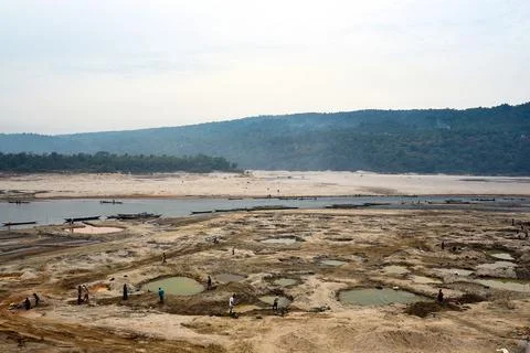 People Exploring a Dry Riverbed by the River, Boats Lined Shore Stock Photos