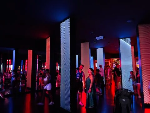 People exploring an interactive LED light exhibit with colorful pillars and.. Stock Photos