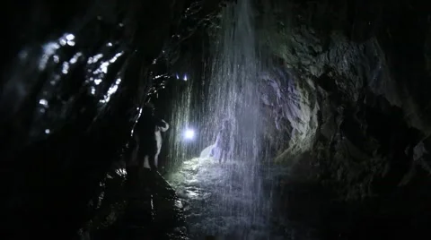 People exploring the waterfall in a deep cave Stock Footage 51633912