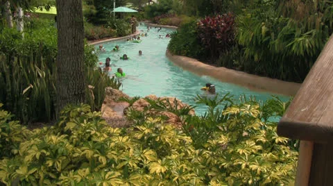 People in Fast-flowing Lazy River Nestled Behind Tropical Plants Stock Footage 24711242