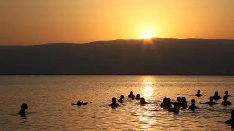 People float in the dead sea during sunrise Stock Footage