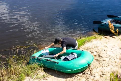 People float down a calm river in Europe in inflatable rubber boats. Stock Photos