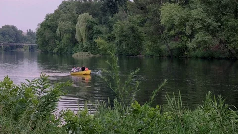 People float in a rowing boat along the river between green trees. Stock Footage 112301934