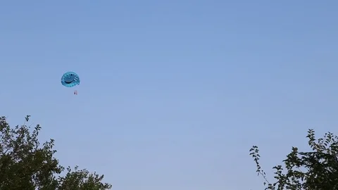People flying on parachute in blue sky. Parasailing. Stock Footage