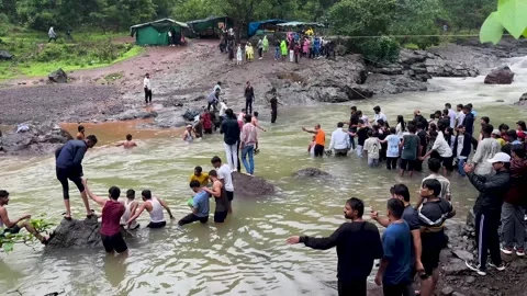 People forming a human chain to help others cross a flowing river in India Stock Footage 340251795