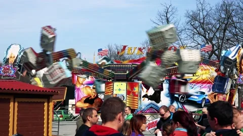 People in funfair stand in front of fairground attraction which turns around Stock Footage 61966718