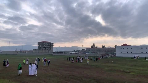 People gathering during Eid al-Adha morning under dramatic cloudy sky Stock Footage 311453315