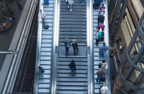 People going up and down by the escalator in the main train station. Stock Photos