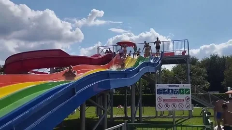 People going down the slide into the swimming pool Stock Footage 328427187