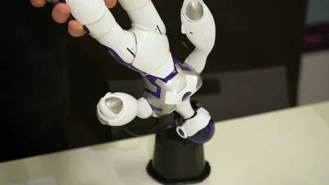 People hand making battery replacement feet of small white toy robot to charge Stock Footage 113298128