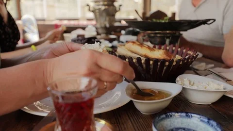 People have breakfast at a table in a cafe, woman puts honey on a piece of pita Stock Footage 123535335