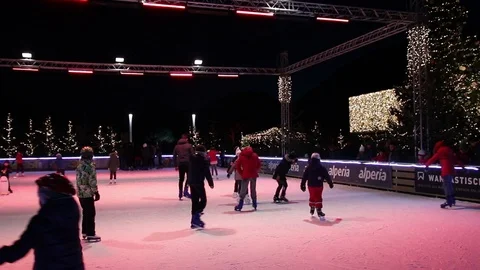 People have fun ice-skating surrounded by Christmas decorations Stock Footage 100089166