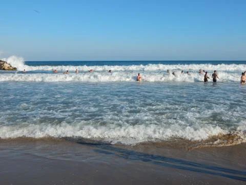 People having fun on the high waves. Waves on the sandy beach Stock Photos