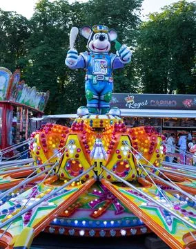 People having fun on swing rides and game booths at an outdoor fairground Stock Photos