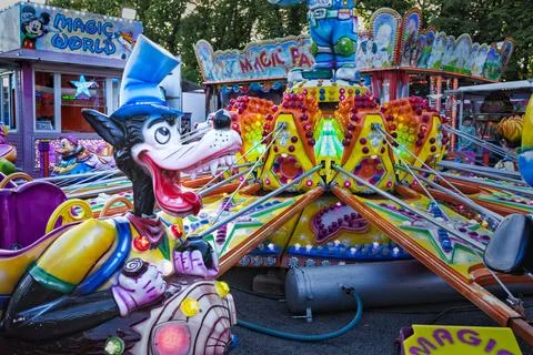 People having fun on swing rides and game booths at an outdoor fairground Stock Photos
