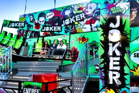 People having fun on swing rides and game booths at an outdoor fairground Stock Photos