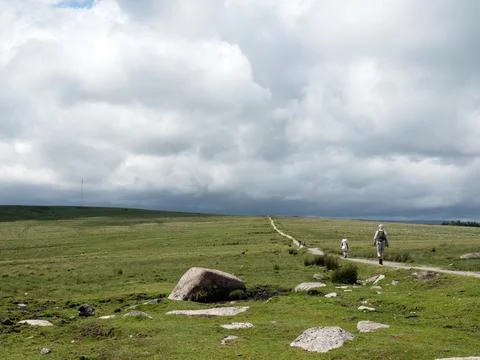 People hike on path under dramatic sky in englands national nature reserve .. Stock Photos
