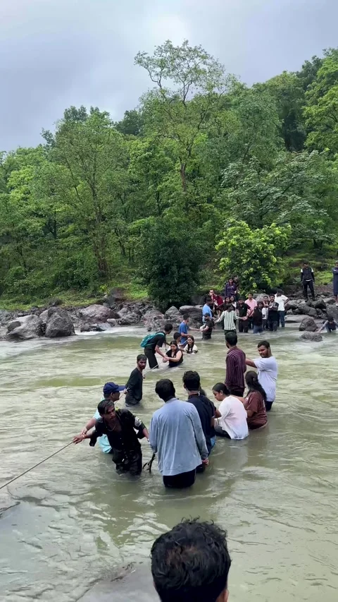 People holding hands and using a rope to safely cross a river together Stock Footage 340251813