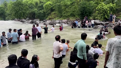 People holding hands and using rope to cross a river in a forest 4K video Stock Footage 340251818