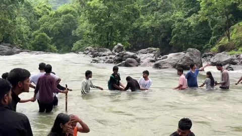 People holding hands and using a rope to safely cross a strong river current Stock Footage 340251832