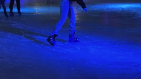 People ice skating on a glowing blue indoor rink, showcasing active leisure and Stock Footage 345665574