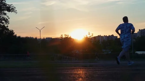 People on a jog against the backdrop of the sunset at the stadium Stock Footage 197366433