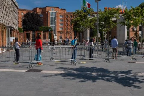 People keep their distance while waiting in line outside a hospital in Italy Stock Photos