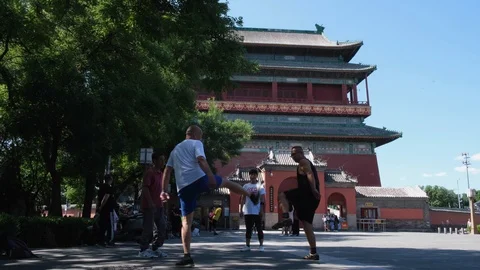 People kick shuttlecock in front of the tourism spot Drum Tower Stock Footage