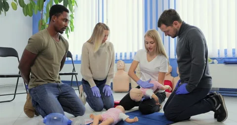 People learning how to safe a life when the baby is choked sitting together with Stock Footage 163976584