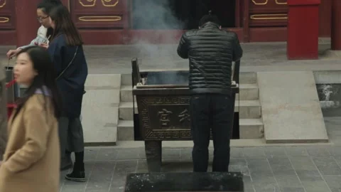 People Lighting Incense and Praying at Outdoor Burner in Beijing Temple Stock Footage 345829330