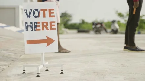 People in line waiting for casting vote near polling booth vote here sign board Stock Footage 196982600