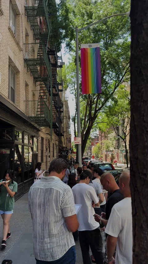 People Lining Up Outside Restaurant Under Rainbow Flag in Manhattan on Sunny Day Stock Footage 341128618