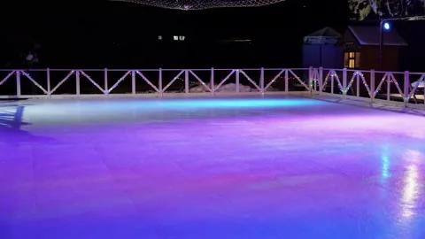 People look at the empty night skating rink in the city with neon lights Stock Footage 156937518