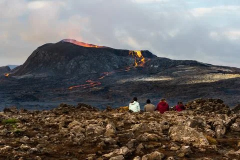 People looking at an Active Volcano with exploding red Lava in Iceland Stockfoto's