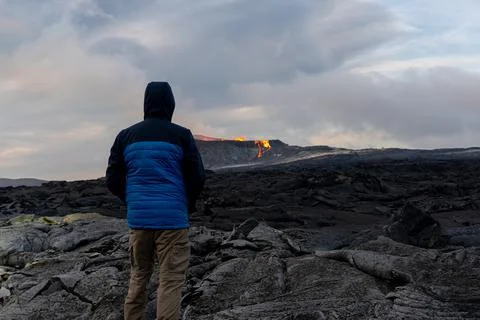 People looking at an Active Volcano with exploding red Lava in Iceland Stockfoto's