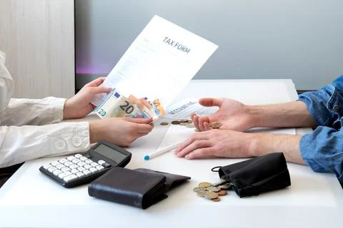 People looking at a tax form at a table with euro banknotes, coins, a calcula Stock Photos