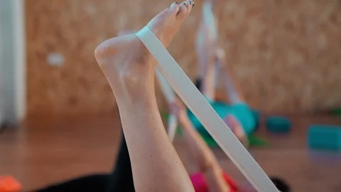 People on the mat pulls on the leg elastic band for Pilates. Stock Footage 93320390