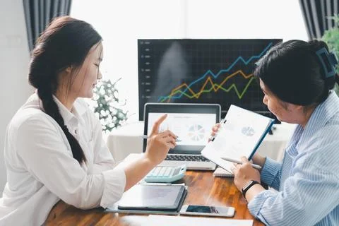 People meeting using laptop computer, calculator, stock market chart paper .. Stock Photos