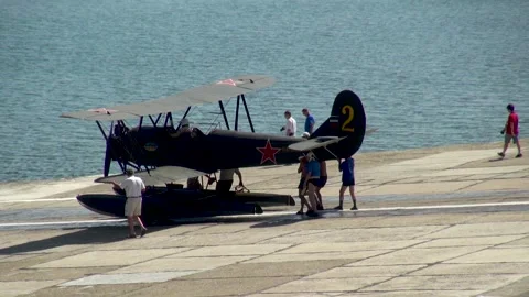 People move seaplane U-2 or Po-2 (NATO: "Mule") from parking lot to sea. Stock Footage 134557377
