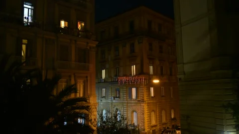 People moving inside illuminated windows of an old building at night Stock Footage 325302554