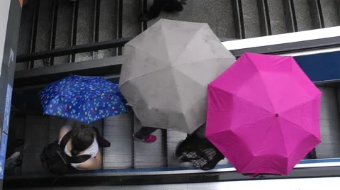 People opening umbrellas on escalator Stock Footage