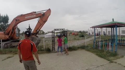 People Pass Through a Passage in an Iron Fence Near Which Stands Tractor View Stock Footage 62568829