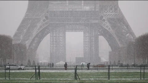 People passing by the Eiffel tower in Paris on a day with heavy snow Stock Footage 290051897