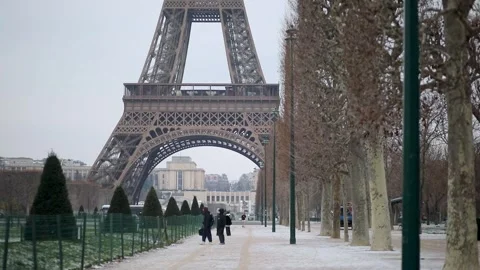 People passing by the Eiffel tower in Paris on a snowy day Stock Footage 317102740