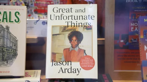 People Passing A Shop Are Reflected In A Window Displaying Arday’s Book 库存影片 345108040