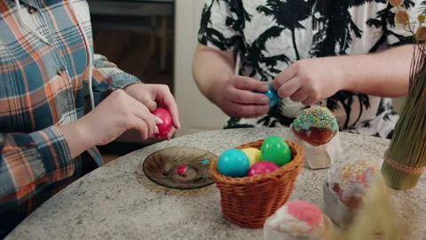 People peeling vibrant Easter eggs amidst sweet treats and warm glow Video stock 330498201
