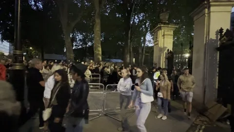 PEOPLE PEER THROUGH GATE BUCKINGHAM PALACE PAYING RESPECTS TO QUEEN ELIZABETH II Stock Footage 208958013