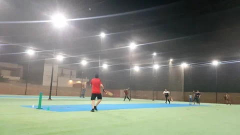 People playing cricket in cage covered with net at night. Stock Footage 346105335