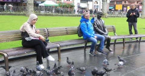 People posing with statue of Rowan Atkinson comic character Leicester Square Stock Footage 321017461